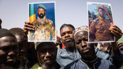 Demonstrators gathering in Ouagadougou to show support on January 25, 2022 to the military hold a picture of Colonel Aissimi Goita (L), the Malian military officer who has served as interim President of Mali since May 24, 2021, and of Lieutenent Colonel Paul-Henri Sandaogo Damiba the leader of the mutiny and of the Patriotic Movement for the Protection and the Restauration (MPSR)