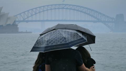 Tourists are seen looking at The Sydney Harbour Bridge in the rain on 17 January 2020.