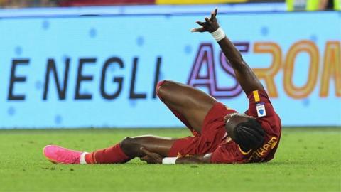 Roma striker Tammy Abraham lies injured on the pitch