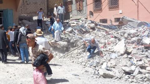 People running from rubble next to buildings in Morocco