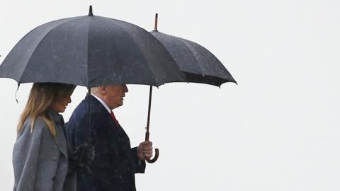 Donald and Melania Trump are pictured under umbrellas walking to the Armistice Ceremony at the Arc de Triomphe, Paris.