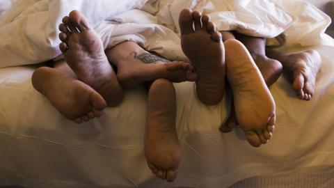 The feet of several people sharing a bed