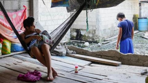 A woman in a hammock near a destroyed wall