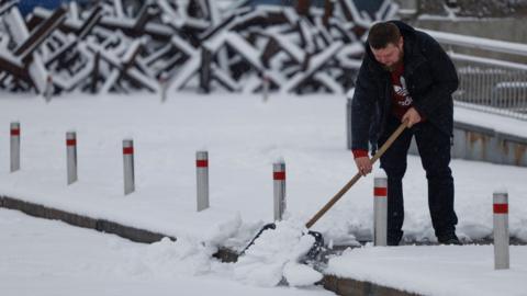 A man shovels snow in Kyiv