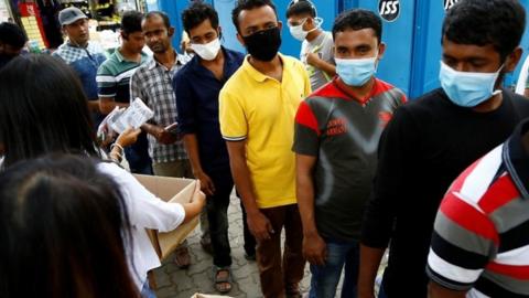 Migrant workers queue for supplies in Singapore