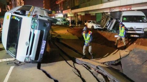 Police officers inspect damaged cars and the road after a suspected gas explosion injured people and caused significant damage, in the central business district of Johannesburg, South Africa July 19, 2023.