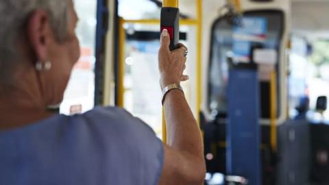 A lady pressing the stop button on a bus