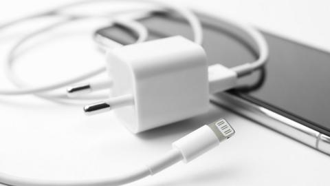 iPhone charging cable and USB power adapter lying on top of an iPhone