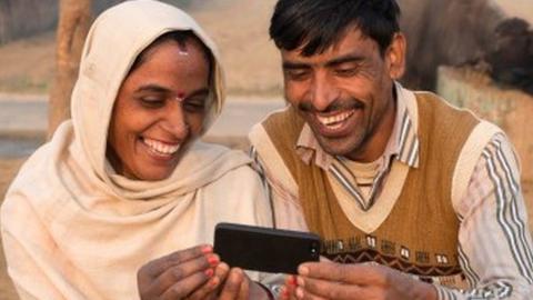 Two people look at a smartphone in rural India
