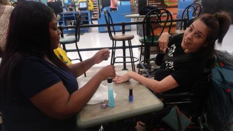 A picture of Ebony Harris painting the nails of Angela Peters