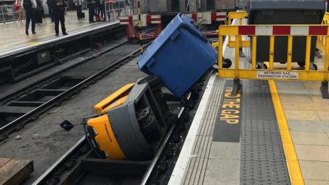 A rubbish dumpster and the vehicle towing it blocking platform one at Paddington