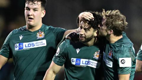 Ollie Hulbert (centre) celebrates with team mates after his winner against Caernarfon.