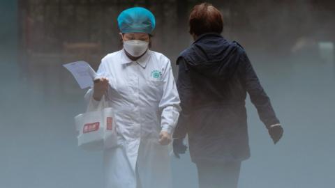 A medical personnel leaves while another person enters a hospital in Shanghai, China.
