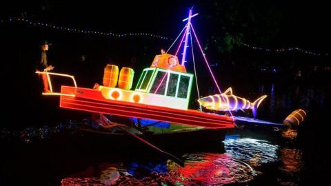 A glowing Jaws-themed boat at night