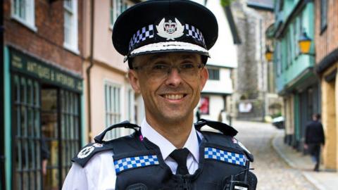 Chief Constable Paul Sanford in uniform, standing in a Norfolk street, smiling and looking straight to the camera 