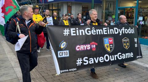 Dragons and Ospreys fans march together to Rodney Parade ahead of the game between the two sides, in a protest aimed at the Welsh Rugby Union's plans to cut a professional region