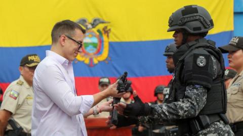 President of Ecuador Daniel Noboa gives a rifle to a police officer during the event to supply weaponry to the armed forces on August 6, 2024 in Duran, Ecuador. 