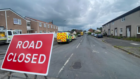 A sign saying road closed and a police van