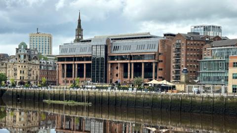 The  Newcastle Crown Court building reflected in a river.