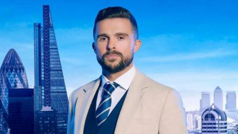 A close up shot of Phil Turner wearing a jacket and tie looking to camera with a London skyline backdrop