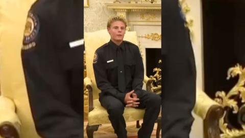 Young man with blonde hair in all black shirt, tie and trousers.
