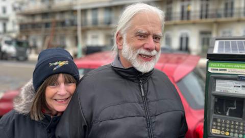 Two Brighton residents Christina and Gordon Westwell pictured on Brighton seafront next to a parking machine