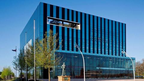 A large cube-shaped glass and black building against a blue sky