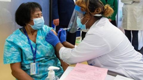 A health-care worker administers the second dose of the Pfizer-BioNTech vaccine in Toronto, Canada