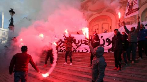 Tunisian protesters light flares and shout slogans during a celebration to mark the seventh anniversary of the uprising that ousted president Zine El Abidine Ben Ali