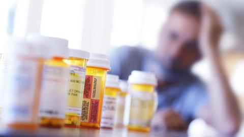 A large group of prescription medication bottles sit on a table