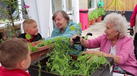 Schoolchildren and the care home residents gardening