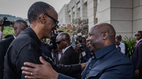 Rwandan President Paul Kagame (L) is greeted by Burundi's President Evariste Ndayishimiye (R) as he arrives for the extraordinary Summit of East African Community Heads of State at the state house in Bujumbura, Burundi, on February 4, 2023