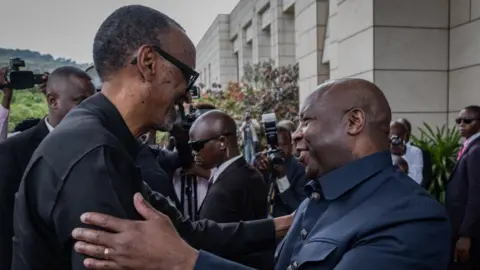 Rwandan President Paul Kagame (L) is greeted by Burundi's President Evariste Ndayishimiye (R) as he arrives for the extraordinary Summit of East African Community Heads of State at the state house in Bujumbura, Burundi, on February 4, 2023