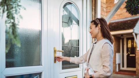 Young woman opening front door with key