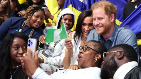 Meghan, Duchess of Sussex Prince, and Prince Harry, Duke of Sussex, take selfies with fans as they attend the Ukraine Nigeria Mixed Team Preliminary Round - Pool A Sitting Volleyball match during day five of the Invictus Games Düsseldorf 2023 on September 14, 2023 in Duesseldorf, Germany.