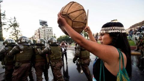 A Mapuche indigenous woman protests next to riot police for the death of Mapuche Camilo Catrillanca in Santiago, November 15, 2018.