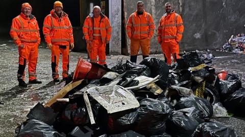 Refuse workers next to sacks of rubbish