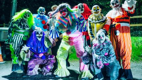 Scary clowns in multi-coloured outfits and wigs