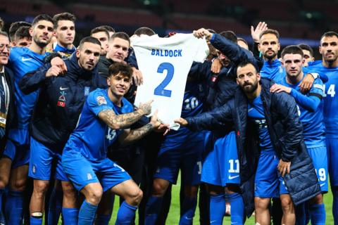 Greece players hold up a Baldock 2 shirt