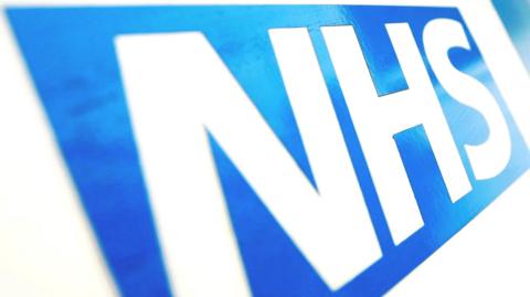 A stock photo of the NHS logo, which consists of white letters on a blue background.