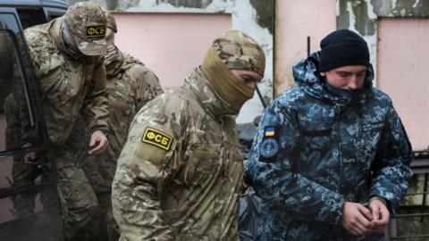 A Russian FSB security service officer escorts a detained Ukrainian sailor to a courthouse in Simferopol, Crimea, on November 27, 2018