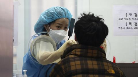 A medical professional takes samples from people at a testing centre in Seoul