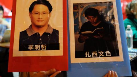 A volunteer holds placards of detained Taiwanese activist Lee Ming-cheh and Tibetan education advocate Tashi Wangchuk in Taipei on June 4, 2017