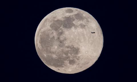 Full Moon with an aeroplane in silhouette flying past  
