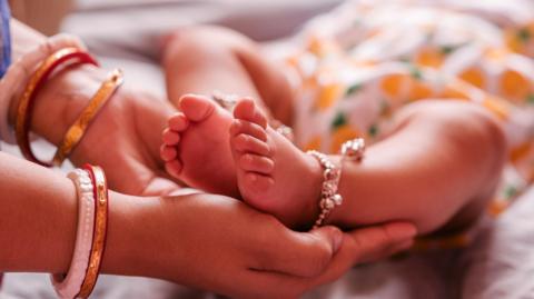 Close up Mother Holding Feet of infant Baby in Her Hand, Baby feet in mother hands. 
