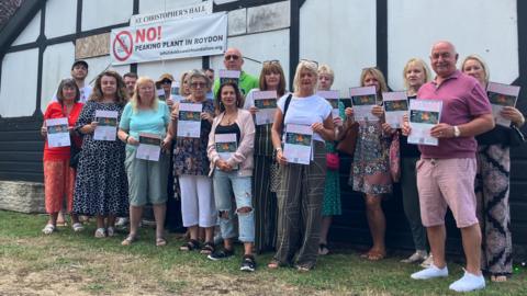 A group of residents holding placards stand in front of St Christopher's Hall in Dobb's Weir