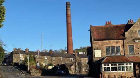 A brick chimney rising above the buildings of Milford