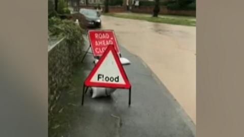 Flood signs and a road deluged by brown water