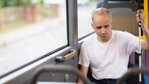 Man with white stick on bus