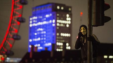 A man in a mask talks on his cell phone